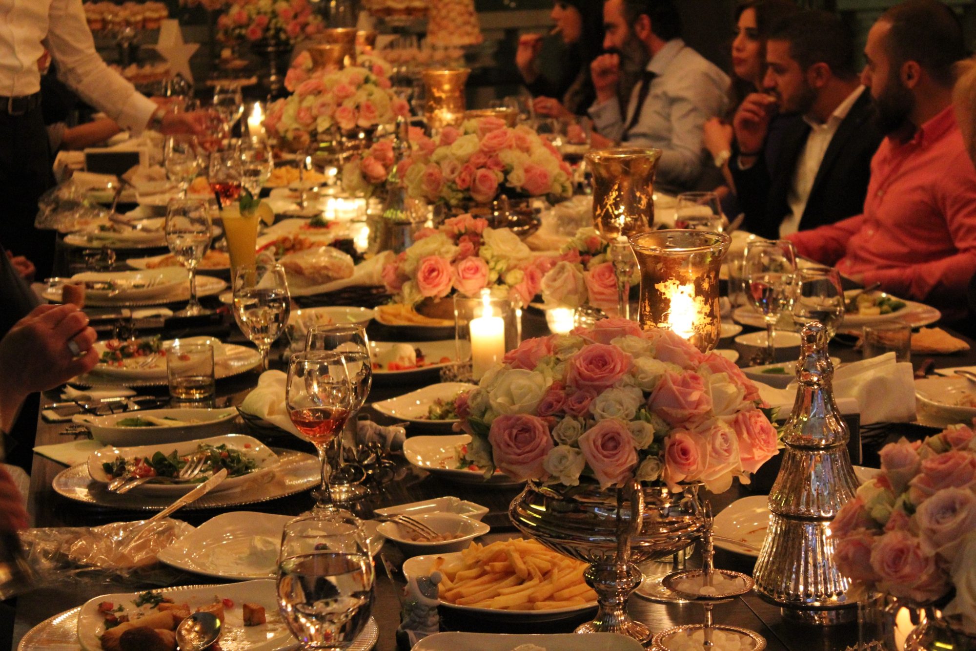 Guests at a candlelit dinner with pink roses in Tulip Lounge